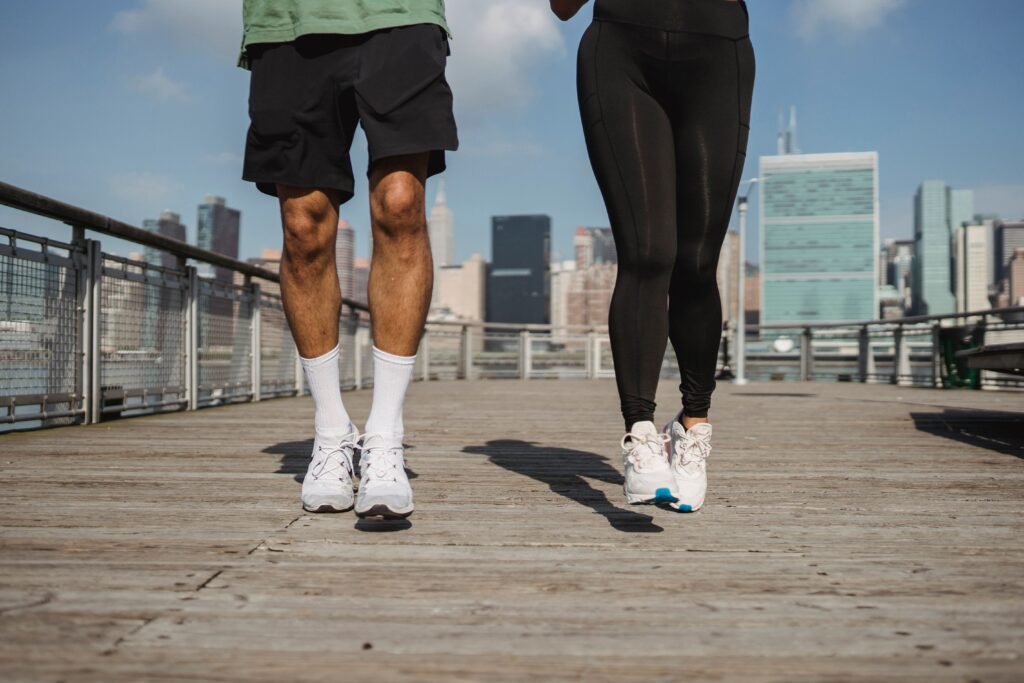 A man and woman jogging on a boardwalk with a city skyline in the background. Dynamic fitness and urban lifestyle.